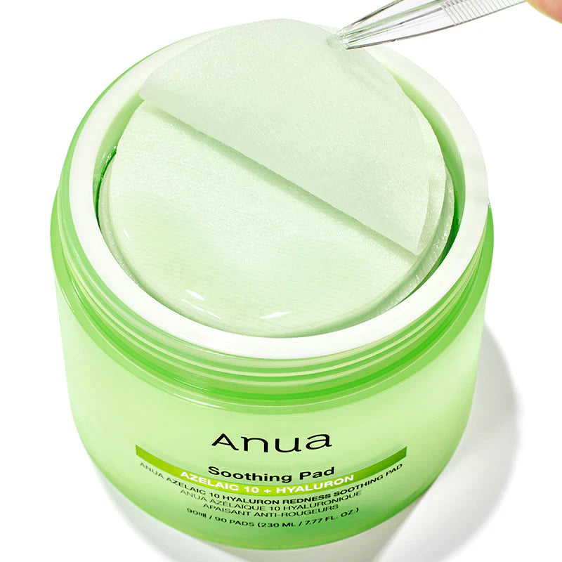 Um frasco verde com a inscrição “Anua Soothing Pad” contém discos circulares embebidos em ácido azelaico e hialuron. Uma pinça levanta um dos discos, sugerindo frescura e cuidado. KBeauty.
