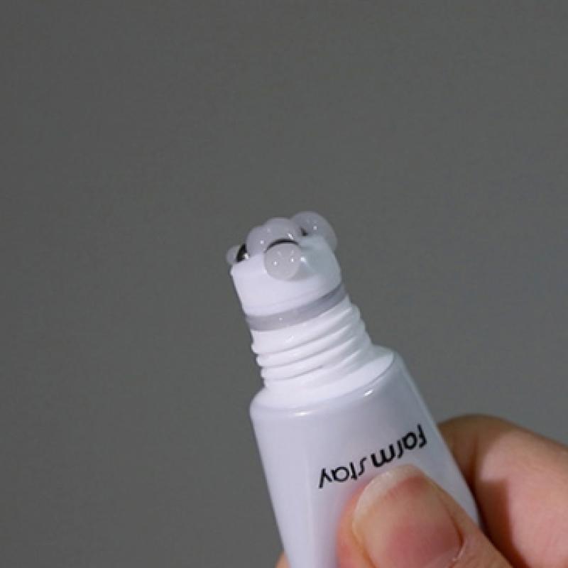Imagem em grande plano da mão de uma pessoa a segurar o Cica Farm Revitalizing Rolling Eye Serum com três esferas metálicas na ponta. O gel transparente é visível. O fundo é cinzento liso.