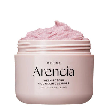 Um frasco rosa rotulado "Arencia Fresh Rosehip Rice Mochi Cleanser", com um creme rosa macio e fofo por cima. Transmite uma sensação hidratante e calmante.