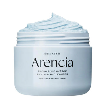 Um frasco do Arencia Fresh Blue Hyssop Rice Mochi Cleanser, aberto para revelar o creme azul-claro. O rótulo destaca os benefícios hidratantes e de limpeza profunda.