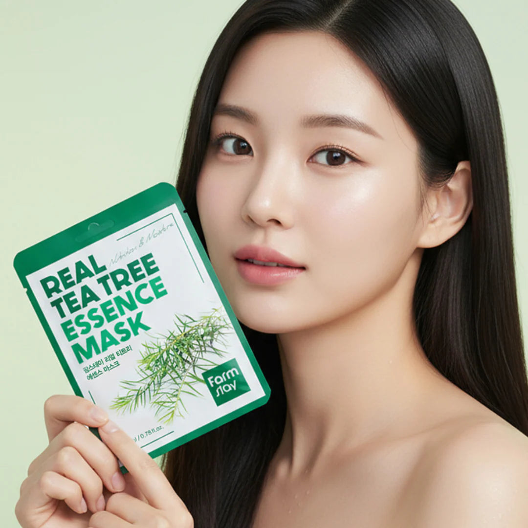 Uma mulher coreano de cabelo comprido e escuro segura um pacote da Real Tea Tree Essence Mask, exibindo pele limpa. A embalagem verde transmite uma sensação fresca e natural.