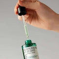 Mão segurando sérum facial coreano com conta-gotas, frasco verde rotulado AHA BHA PHA 30 Days Miracle Serum.