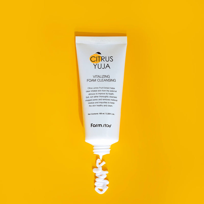 Tubo branco do Citrus Yuja Vitalizing Foam Cleanser sobre um fundo amarelo vibrante. Uma espiral de espuma emerge, transmitindo frescura e vitalidade.