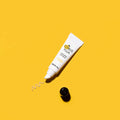 Tubo do Citrus Yuja Vitalizing Lip Balm sobre um fundo amarelo vibrante, com uma pequena mancha do bálsamo visível. A imagem transmite uma sensação de energia e frescura.