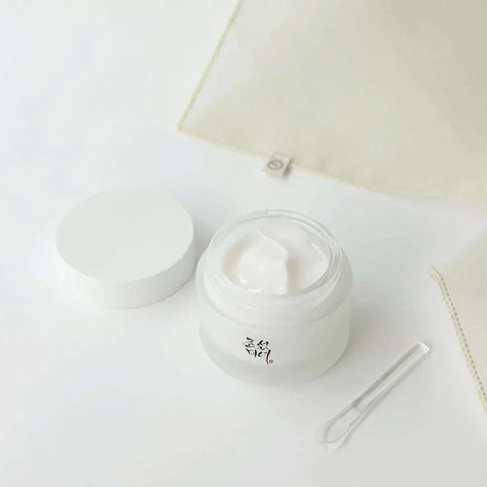 Creme facial hidratante coreano branco em pote aberto sobre superfície clara, com espátula.