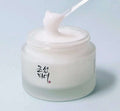 Creme coreano hidratante em pote de vidro transparente com espátula e textura cremosa.