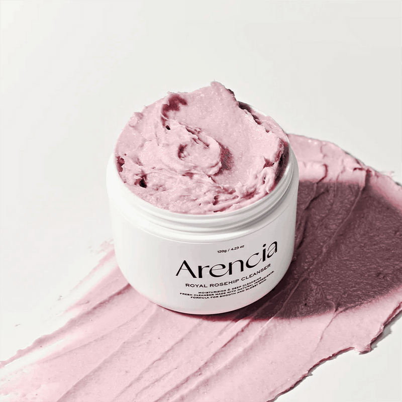 Um frasco rosa rotulado "Arencia Fresh Rosehip Rice Mochi Cleanser", com um creme rosa macio e fofo por cima. Transmite uma sensação hidratante e calmante.