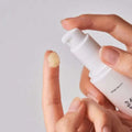 Sérum solar coreano sendo aplicado no dedo, embalagem branca minimalista, cuidado facial