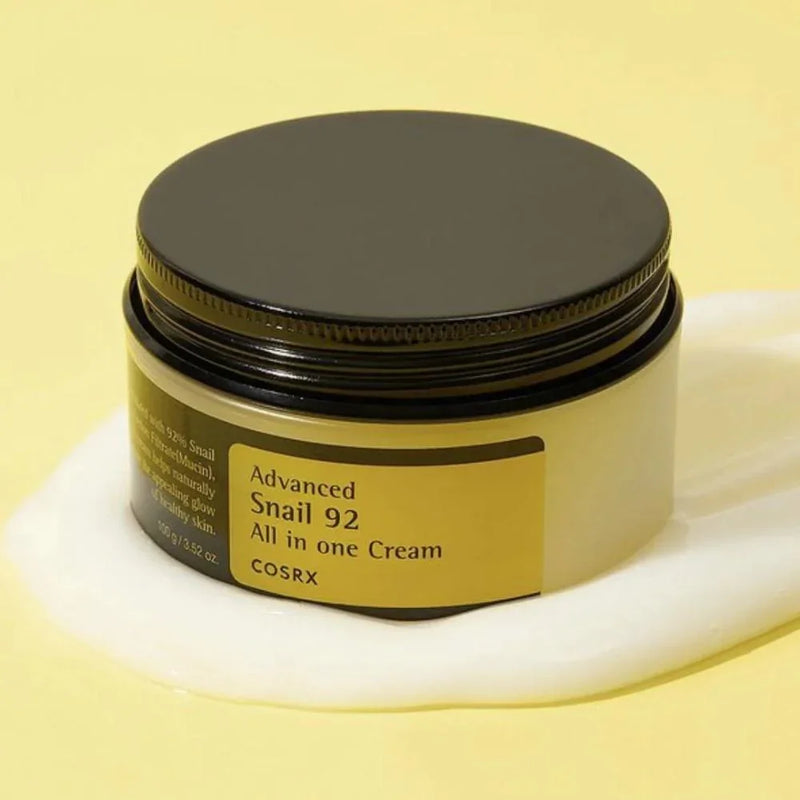 Creme facial coreano COSRX Advanced Snail 92 All in One Cream em pote sobre fundo amarelo.