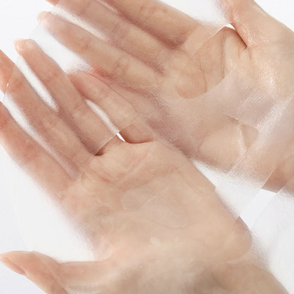  Duas mãos seguram delicadamente uma máscara facial em folha translúcida e brilhante, gelatinosa, a Jelly Seal Dewy Mask - da Dr. Althea revelando a pele suave por baixo. A imagem transmite uma sensação de cuidado da pele e rejuvenescimento.

