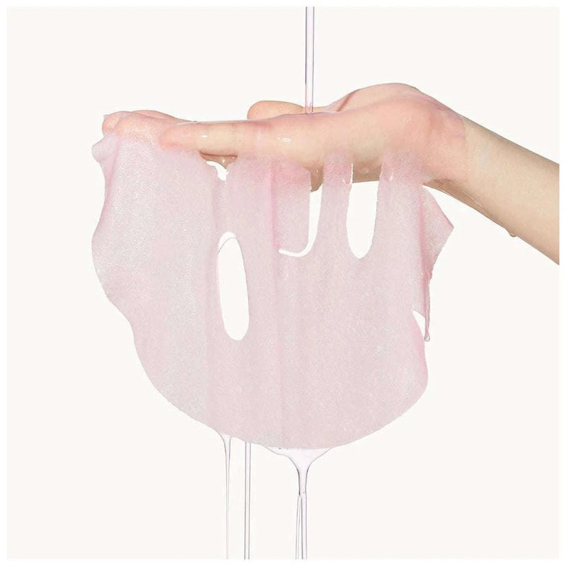 Uma mão segura uma máscara facial rosa translúcida e húmida, pingando água. A textura é delicada e suave, transmitindo uma sensação de frescura e cuidado com a pele.