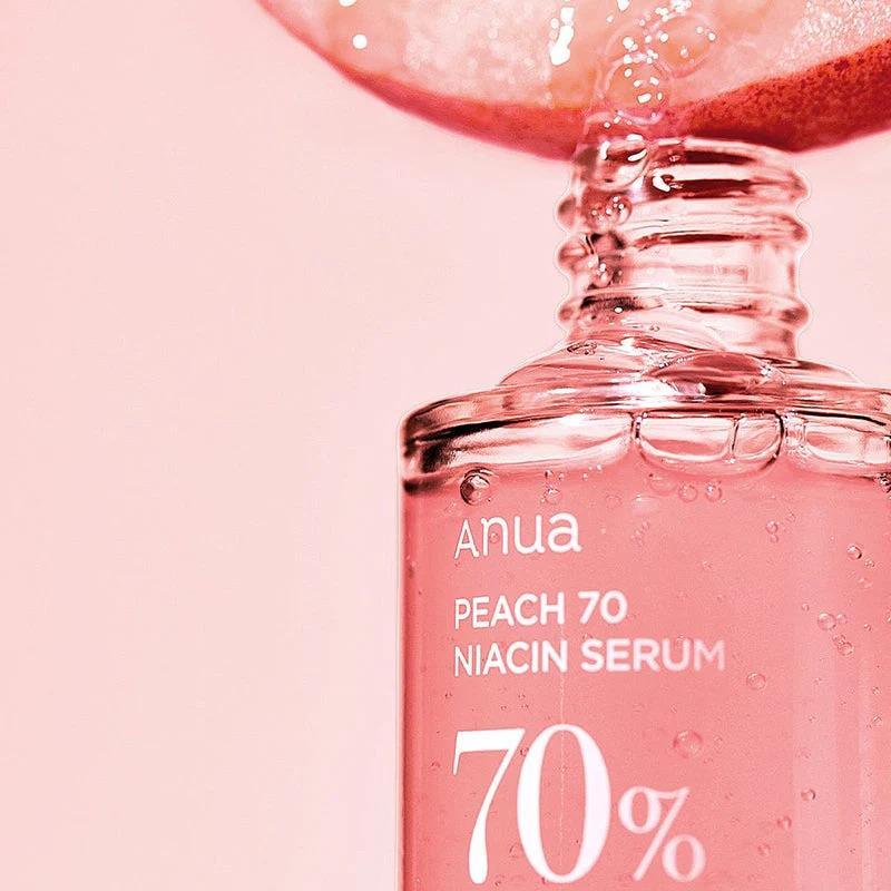 Sérum facial coreano Anua Peach 70 Niacinamide em frasco transparente com líquido rosa, detalhes de pêssego e bolhas.