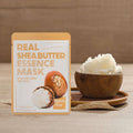 Pacote da Real Shea Butter Essence Mask colocado ao lado de uma tigela de madeira cheia de manteiga de karité cremosa, sobre um tapete de fibras naturais, transmitindo uma sensação natural e nutritiva.