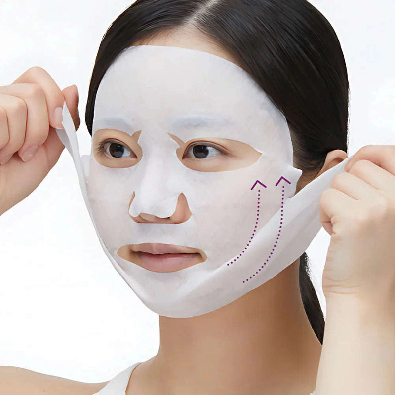 Uma modelo coreana está a aplicar cuidadosamente a máscara facial branca Reedle Shot Lifting Mask da VT Cosmetic no rosto, com movimentos suaves para cima indicados por setas. O ambiente transmite calma e concentrada.