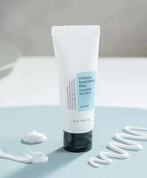 Máscara noturna coreana COSRX Ultimate Nourishing Rice, embalagem de 60ml sobre superfície azul, creme visível.